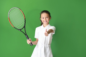 Little girl with tennis racket showing thumb-up on color background