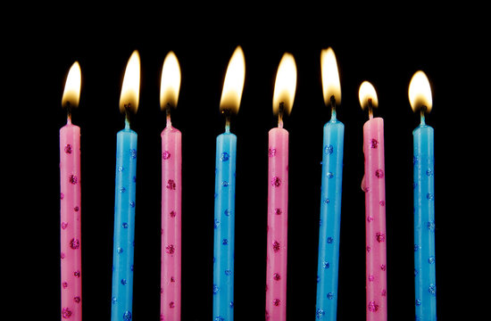 Blue and pink burning birthday candles on black