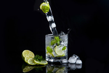 Summer cocktail mojito with splash on black background..