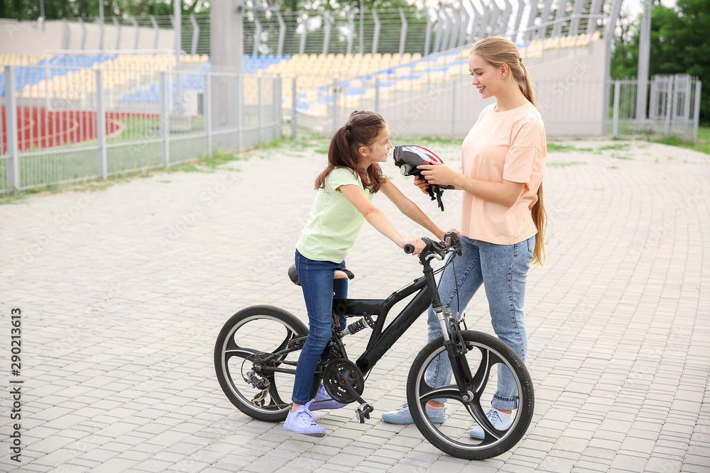 Canvas Prints mother helping her daughter to put on bicycle helmet outdoors