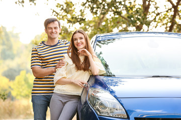 Happy couple near their new car outdoors