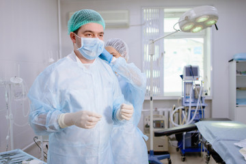 Medical assistant helps a surgeon.