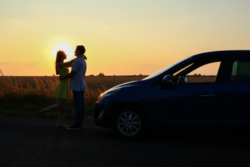 Obraz na płótnie Canvas Silhouette of happy couple near their new car in countryside at sunset