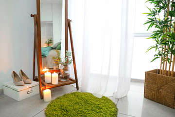 Mirror with burning candles and eucalyptus branches in room