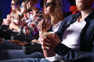 Friends with popcorn watching movie in cinema