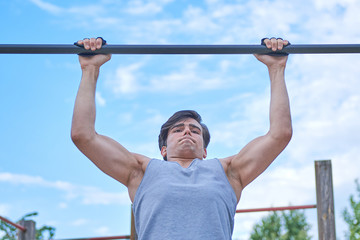 Fototapeta premium a sporty boy doing chin-ups, bottom view