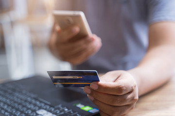 Man using mobile phone and laptop for shopping online by credit card. Pays for purchase.online shopping, online payment,buy and sell products & services.