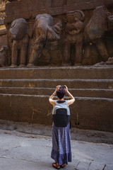 Girl tourist shooting a photo on a smartphone while walking in a Kailash Temple in Ellora. India