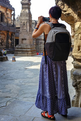 Girl tourist shooting a photo on a smartphone while walking in a Kailash Temple in Ellora. India