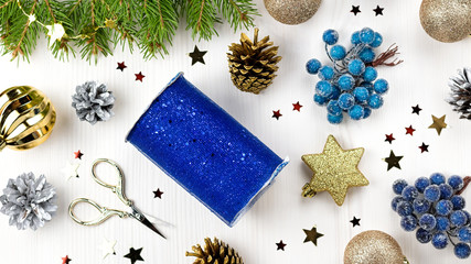 Christmas card with fir branches, giftbox, golden, red and blue decor and wooden ornaments, confetti. Christmas flat lay