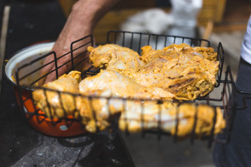 Man puts marinated chicken on a metal grid