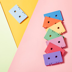 Painted audio cassettes on bright multicolor background, copy space, top view. Retro musical background