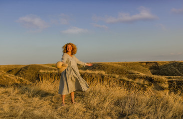 amazing girl in a hat at sunset in the steppe on the sea