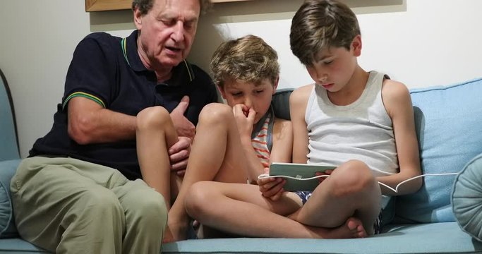 Grand-father with grand-children together looking at tablet