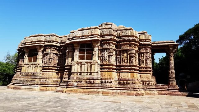 sunlit side view of intricately carved exterior and pillars of the backside of sun temple Modhera which was built in 1026 AD by King Bhimdev of the Solanki dynasty