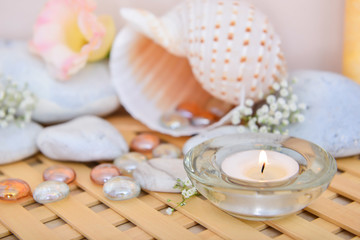 Fototapeta na wymiar Beautiful burning candle with spa stones and seashell on table