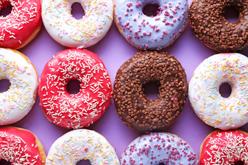 Different tasty donuts on color background