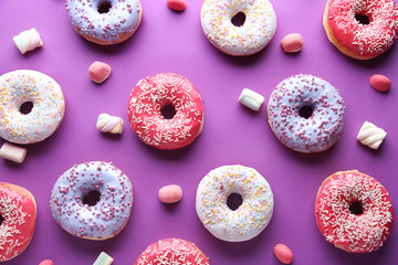 Different tasty donuts with candies on color background