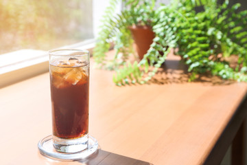 Glass of cold cola on wooden window sill
