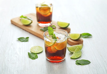 Glasses of cold cola, lime and mint on table