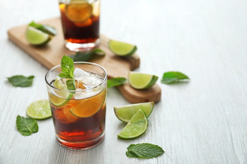 Glasses of cold cola, lime and mint on table