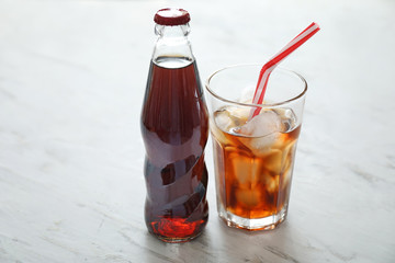 Glass and bottle of cold cola on table