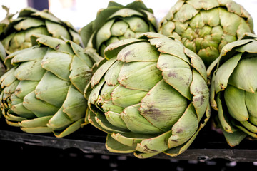Obraz premium Several heads of artichokes on display at a local farmers market.