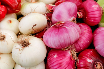 Several white and pink onions on display at a local farmers market.