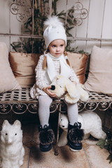 Adorable little cute girl in knitted hat indoors at home. Christmas, winter holidays, childhood concept
