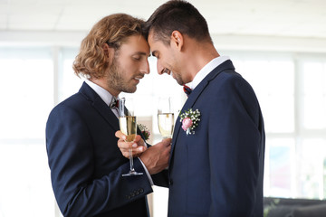 Happy gay couple with champagne on their wedding day at home