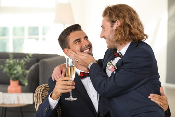 Happy gay couple with champagne on their wedding day at home