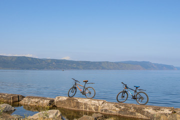 2 bicycles standing on stones against backdrop of Lake Baikal.
