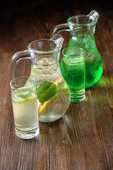 Different soft drinks in transparent jugs on a dark wooden background. menu for catering