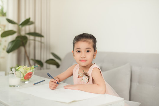Little girl drawing picture at table with painting tools indoors