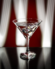 Martini glass isolated on a red background with stripes of neon light painting behind them. Light wave, play of colors, drawing with light.