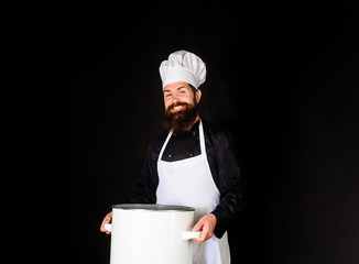 Chef in uniform cooking with casserole. Cooking pot. Chef, cook or baker with saucepan in hand. Professional chef in uniform and hat holds pan. Male chef holds pot. Cooking, food, profession concept.