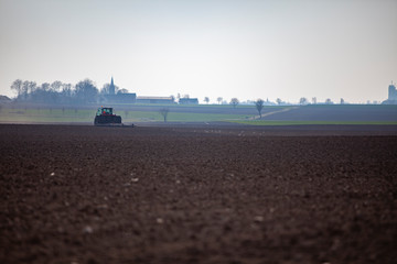  tractor plows the ground in backlight