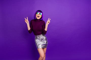 Portrait of charming millennial with eyeglasses eyewear making v-signs wearing turtleneck isolated over purple violet background