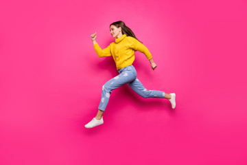 Fototapeta na wymiar Full length profile side photo of concentrated youth jumping running fast looking ahead wearing yellow sweater dotted denim jeans isolated over fuchsia background