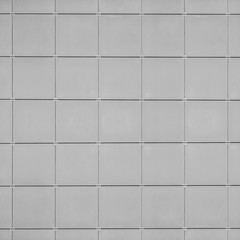 A wall of gray large square tiles with metal fasteners