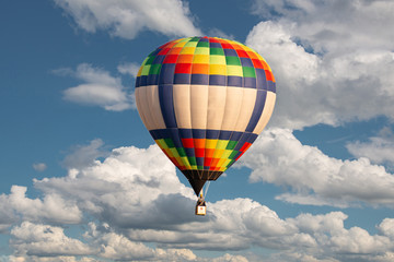 Multicolored balloon floating in the sky on the background of passing fluffy clouds