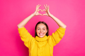 Close up photo of cheerful girl showing heart figure heart enjoying wearing yellow sweater isolated...