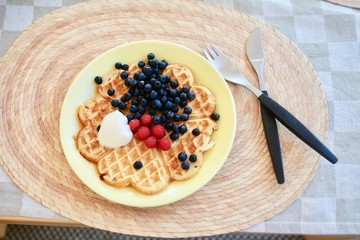 A waffle with fresh berries and whipped cream