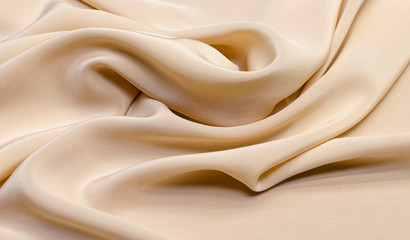Texture, background, pattern. Light beige silk fabric for sewing clothes. Crepe de chine