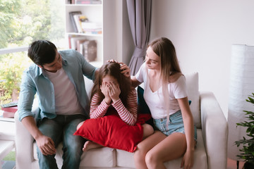 little girl sad and father and mother consoling her at home together, young family concept