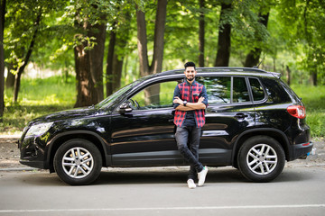 Young handsome indian man standing near his car on the road - Powered by Adobe
