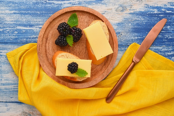 Snack with cheese and blackberries on the wooden plate