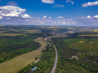 Aerial view of a provincial road passing through a forest and green lands
