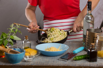 Woman is cooking in the kitchen. Mixing of pasta with sauce in the pan