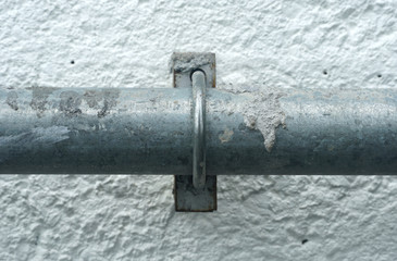 Steel pipe attached to a white concrete wall